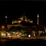 Чудесное Hagia Sophia на предпосылке и ярком кафе со светами на переднем плане к ночь Стамбул, Турция стоковое изображение rf Чудесное Hagia Sophia на предпосылке и ярком кафе со светами на переднем плане к ночь Стамбул, Турция стоковое изображение rf