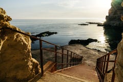 Шаги к пляжу камня моря Заходящее солнце отражено в воде стоковая фотография Шаги к пляжу камня моря Заходящее солнце отражено в воде стоковая фотография