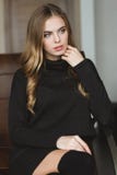 Шикарная заботливая женщина в черном платье сидя на кожаной софе Стоковые Фото Шикарная заботливая женщина в черном платье сидя на кожаной софе Стоковые Фото