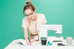 Шить мастерская руки держа работу белошвейки измерения Портрет молодого dressmaker с тетрадью на покрашенной предпосылке стоковое фото rf Шить мастерская руки держа работу белошвейки измерения Портрет молодого dressmaker с тетрадью на покрашенной предпосылке стоковое фото rf