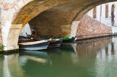 Шлюпки под мостом в Comacchio, Италии стоковые изображения Шлюпки под мостом в Comacchio, Италии стоковые изображения
