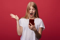 Эмоциональная сотрясенная маленькая девочка в белой футболке смотря мобильный телефон стоковое фото rf Эмоциональная сотрясенная маленькая девочка в белой футболке смотря мобильный телефон стоковое фото rf