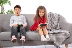 Эмоциональные дети играя видеоигру на софе стоковое изображение Эмоциональные дети играя видеоигру на софе стоковое изображение