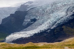 Язык ледника в Исландии перемещаясь вниз от зеленой горы мха в туманном дне Голубой ледниковый лед видим стоковое изображение rf Язык ледника в Исландии перемещаясь вниз от зеленой горы мха в туманном дне Голубой ледниковый лед видим стоковое изображение rf