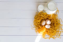 3 яичка цыпленка в декоративном гнезде с кувшином и стеклом молока на белой деревянной предпосылке Стоковые Изображения RF 3 яичка цыпленка в декоративном гнезде с кувшином и стеклом молока на белой деревянной предпосылке Стоковые Изображения RF
