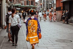 Японская гейша в голубом и желтом кимоно идя вниз с улицы в Gion Киото Японии стоковое изображение Японская гейша в голубом и желтом кимоно идя вниз с улицы в Gion Киото Японии стоковое изображение