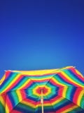 Ярко покрашенные striped зонтик пляжа и небо ясности голубое стоковые изображения Ярко покрашенные striped зонтик пляжа и небо ясности голубое стоковые изображения