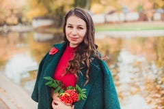一个少妇在秋天公园走 穿一件绿色外套和红色礼服的深色的妇女 库存照片 一个少妇在秋天公园走 穿一件绿色外套和红色礼服的深色的妇女 库存照片