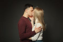 一对美好的年轻夫妇的画象在摆在黑暗的背景的演播室的爱的 亲吻的人和的女孩紧密 免版税库存照片 一对美好的年轻夫妇的画象在摆在黑暗的背景的演播室的爱的 亲吻的人和的女孩紧密 免版税库存照片