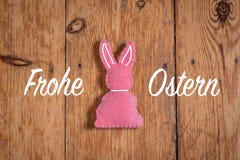 与文本‘Frohe Ostern‘和木背景的桃红色复活节兔子 翻译:‘复活节快乐‘ 免版税库存图片 与文本‘Frohe Ostern‘和木背景的桃红色复活节兔子 翻译:‘复活节快乐‘ 免版税库存图片