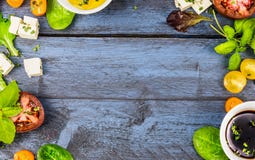 与沙拉成份的食物框架:油、醋、蕃茄、蓬蒿和乳酪在蓝色土气木背景 库存照片 与沙拉成份的食物框架:油、醋、蕃茄、蓬蒿和乳酪在蓝色土气木背景 库存照片