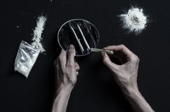 与药物和毒瘾题目的战斗:手上瘾者谎言在一张黑暗的桌上和在它附近是药物,顶面演播室 免版税库存图片 与药物和毒瘾题目的战斗:手上瘾者谎言在一张黑暗的桌上和在它附近是药物,顶面演播室 免版税库存图片