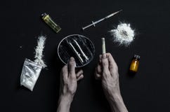 与药物和毒瘾题目的战斗:手上瘾者谎言在一张黑暗的桌上和在它附近是药物 免版税库存图片 与药物和毒瘾题目的战斗:手上瘾者谎言在一张黑暗的桌上和在它附近是药物 免版税库存图片