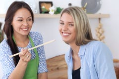 两名年轻愉快的妇女在厨房里烹调 朋友获得乐趣,当preapering健康和鲜美膳食时 免版税库存图片 两名年轻愉快的妇女在厨房里烹调 朋友获得乐趣,当preapering健康和鲜美膳食时 免版税库存图片