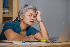办公室工作在手提电脑书桌上的哀伤和沮丧的成熟可爱的亚裔妇女生活方式画象被注重和疲乏 图库摄影 办公室工作在手提电脑书桌上的哀伤和沮丧的成熟可爱的亚裔妇女生活方式画象被注重和疲乏 图库摄影