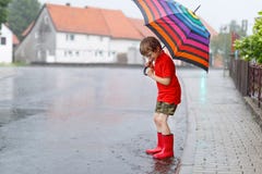 哄骗穿红色雨靴和走与伞的男孩 免版税库存图片 哄骗穿红色雨靴和走与伞的男孩 免版税库存图片