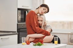在爱的肉欲和嫩年轻女同性恋的夫妇,拥抱在厨房里,当吃早餐妇女时为每天是愉快的 免版税库存照片 在爱的肉欲和嫩年轻女同性恋的夫妇,拥抱在厨房里,当吃早餐妇女时为每天是愉快的 免版税库存照片