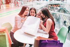 女孩坐在桌上并且调查购物袋 他们是愉快和非常激动的 库存图片 女孩坐在桌上并且调查购物袋 他们是愉快和非常激动的 库存图片