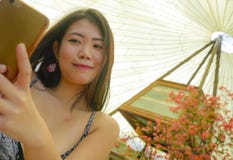 微笑年轻俏丽和愉快的亚裔韩国旅游的妇女拿着拍自画象selfie照片的手机户外在bea 免版税库存图片 微笑年轻俏丽和愉快的亚裔韩国旅游的妇女拿着拍自画象selfie照片的手机户外在bea 免版税库存图片