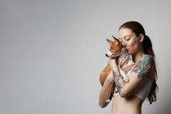 拥抱和亲吻她小的小狗basenji狗的一逗人喜爱的被刺字的年轻女人的画象 在狗和所有者之间的爱 免版税图库摄影 拥抱和亲吻她小的小狗basenji狗的一逗人喜爱的被刺字的年轻女人的画象 在狗和所有者之间的爱 免版税图库摄影