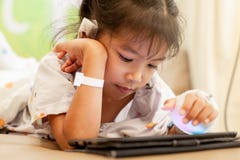 有IV被包扎的解答演奏数字片剂放松的病的亚裔小孩女孩 图库摄影 有IV被包扎的解答演奏数字片剂放松的病的亚裔小孩女孩 图库摄影