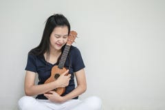 有尤克里里琴的特写镜头亚裔妇女在白水泥墙壁纹理背景 免版税库存图片 有尤克里里琴的特写镜头亚裔妇女在白水泥墙壁纹理背景 免版税库存图片