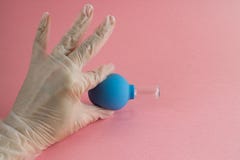 有法式修剪的女性手在医学手套拿着真空面部按摩的蓝色化妆医疗瓶子在桃红色背景 免版税库存图片 有法式修剪的女性手在医学手套拿着真空面部按摩的蓝色化妆医疗瓶子在桃红色背景 免版税库存图片