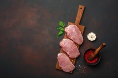 未加工的猪肉牛排片断与蓬蒿、大蒜、胡椒、盐和香料灰浆在切板和生锈的棕色背景的与空间 免版税库存照片 未加工的猪肉牛排片断与蓬蒿、大蒜、胡椒、盐和香料灰浆在切板和生锈的棕色背景的与空间 免版税库存照片