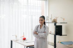 注视着某事的微笑的美好的亚洲女性医生身分和发怒胳膊画象医院,愉快和正面thinkin 图库摄影 注视着某事的微笑的美好的亚洲女性医生身分和发怒胳膊画象医院,愉快和正面thinkin 图库摄影