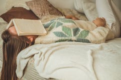 睡觉在与盖她的面孔的书的床上的美丽的年轻女人,因为看书用准备学院检查 库存图片 睡觉在与盖她的面孔的书的床上的美丽的年轻女人,因为看书用准备学院检查 库存图片