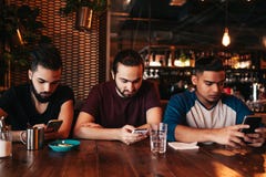 社会网络瘾概念 看他们的在酒吧的混合的族种朋友电话 使用smarphones的阿拉伯人 免版税图库摄影 社会网络瘾概念 看他们的在酒吧的混合的族种朋友电话 使用smarphones的阿拉伯人 免版税图库摄影