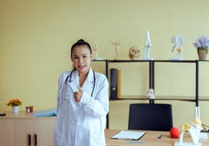 站立和显示标志的微笑的美丽的亚裔妇女医生画象重击在医院,愉快和积极态度 库存照片 站立和显示标志的微笑的美丽的亚裔妇女医生画象重击在医院,愉快和积极态度 库存照片