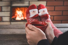 红色咖啡在女性手上由壁炉 女性由在圣诞节红色袜子的warmfire放松 圣诞节节假日 免版税库存照片 红色咖啡在女性手上由壁炉 女性由在圣诞节红色袜子的warmfire放松 圣诞节节假日 免版税库存照片