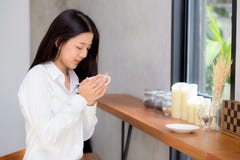 美丽的年轻亚裔妇女饮用的咖啡和微笑在咖啡馆,坐在咖啡店的女孩的早晨 库存图片 美丽的年轻亚裔妇女饮用的咖啡和微笑在咖啡馆,坐在咖啡店的女孩的早晨 库存图片