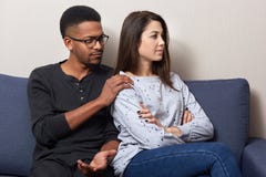 被触犯的可爱的妇女回到她的丈夫坐在平,非洲男性的沙发接触女孩的肩膀并且要求忘记 免版税库存图片 被触犯的可爱的妇女回到她的丈夫坐在平,非洲男性的沙发接触女孩的肩膀并且要求忘记 免版税库存图片