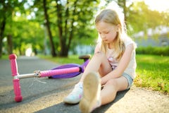 逗人喜爱的小女孩坐地面在落她的滑行车在夏天公园以后 受到伤害的孩子,当乘坐反撞力scoote时 免版税库存图片 逗人喜爱的小女孩坐地面在落她的滑行车在夏天公园以后 受到伤害的孩子,当乘坐反撞力scoote时 免版税库存图片