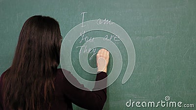 在线教育 女教师举办网络英语课 她在黑板上用粉笔书写语法规则影视素材 视频包括有耳机 教育 在线教育 女教师举办网络英语课 她在黑板上用粉笔书写语法规则影视素材 视频包括有耳机 教育