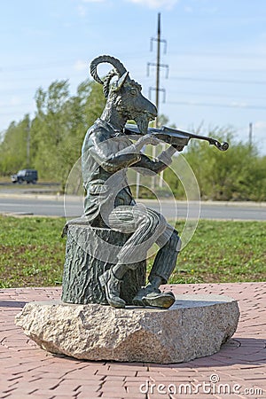Abakan, Russia 05/02/2020: Bronze monument, a goat dressed in a tailcoat plays the violin while sitting on a stump Stock Photo