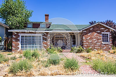 Abandoned Brick Home With Overgrown Front Yard Stock Photo