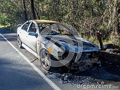 Abandoned burnt out car at the road side front image Stock Photo