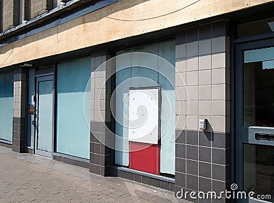 Abandoned closed high street bank or store front with boarded up and covered windows Stock Photo