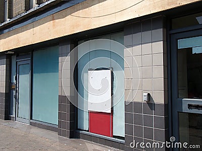 Abandoned closed high street bank or store front with boarded up and covered windows Stock Photo