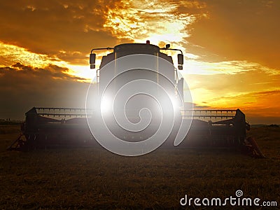 Abandoned combine harvest wheat in the middle of a farm field. Morning yellow wheat field on the sunset cloudy orange sky. Stock Photo