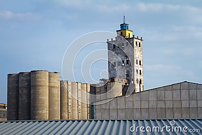 Abandoned damaged old granary against town and blue cloudy sky Stock Photo