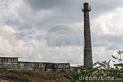 Abandoned factory pipe behind the fence Stock Photo