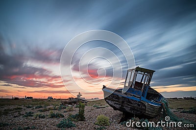 Abandoned fishing boat on beach landscape at sunset Stock Photo