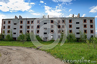 Abandoned four-story multi-entrance brick building on a summer day Stock Photo