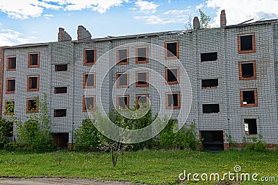 Abandoned four-story multi-entrance brick building on a summer Stock Photo