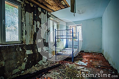 Abandoned hostel. Creepy dirty and abandoned bedroom with cracked walls and double-decker bed Stock Photo