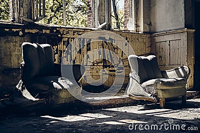Abandoned house with two worn-out sofas and broken windows during daytime Stock Photo